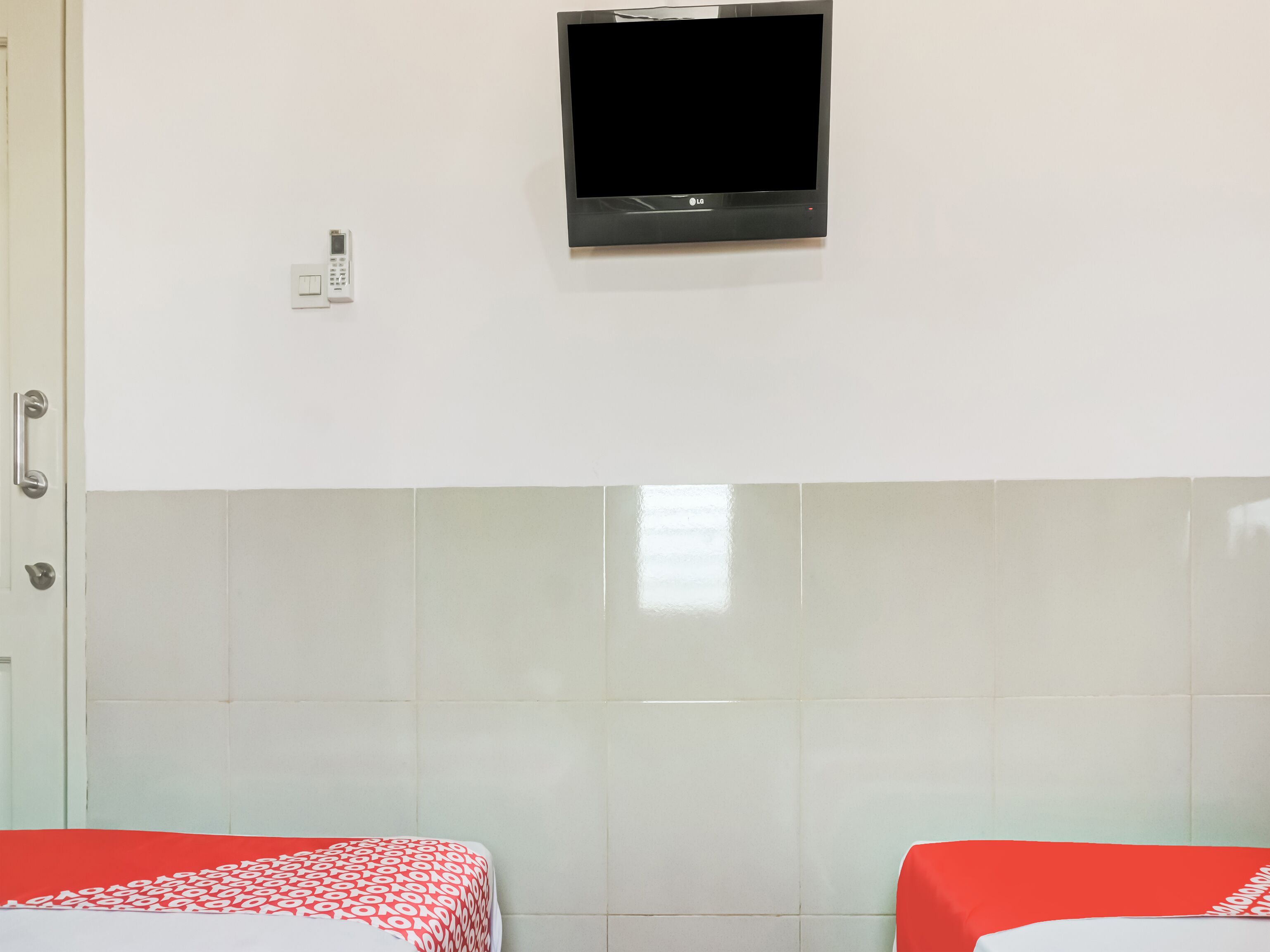 A hotel room with a bed, a TV mounted on the wall, and a door with a handle.