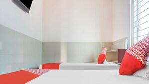 A hotel room with two beds, each with a red and white patterned pillow, and a small desk with a chair. - OYO 91316 Hh Guest House Makassar (Makassar)
