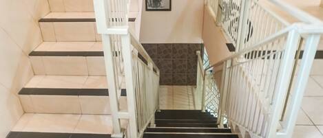 A staircase with white railings and black steps, leading to a lower floor.