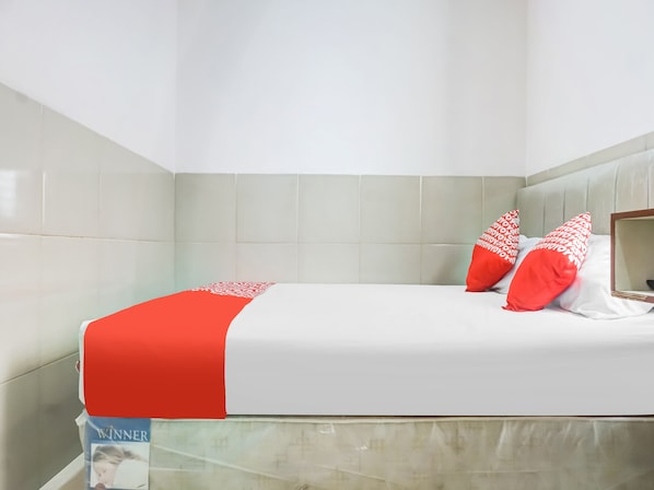 Une chambre d’hôtel avec un lit, une tête de lit et un miroir.