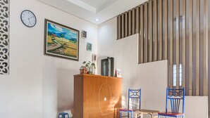 A modern living room with a wooden cabinet, a painting, and a clock on the wall. - OYO 91316 Hh Guest House Makassar (Makassar)
