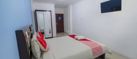 A bedroom with a bed, a wardrobe, a mirror, and a television.