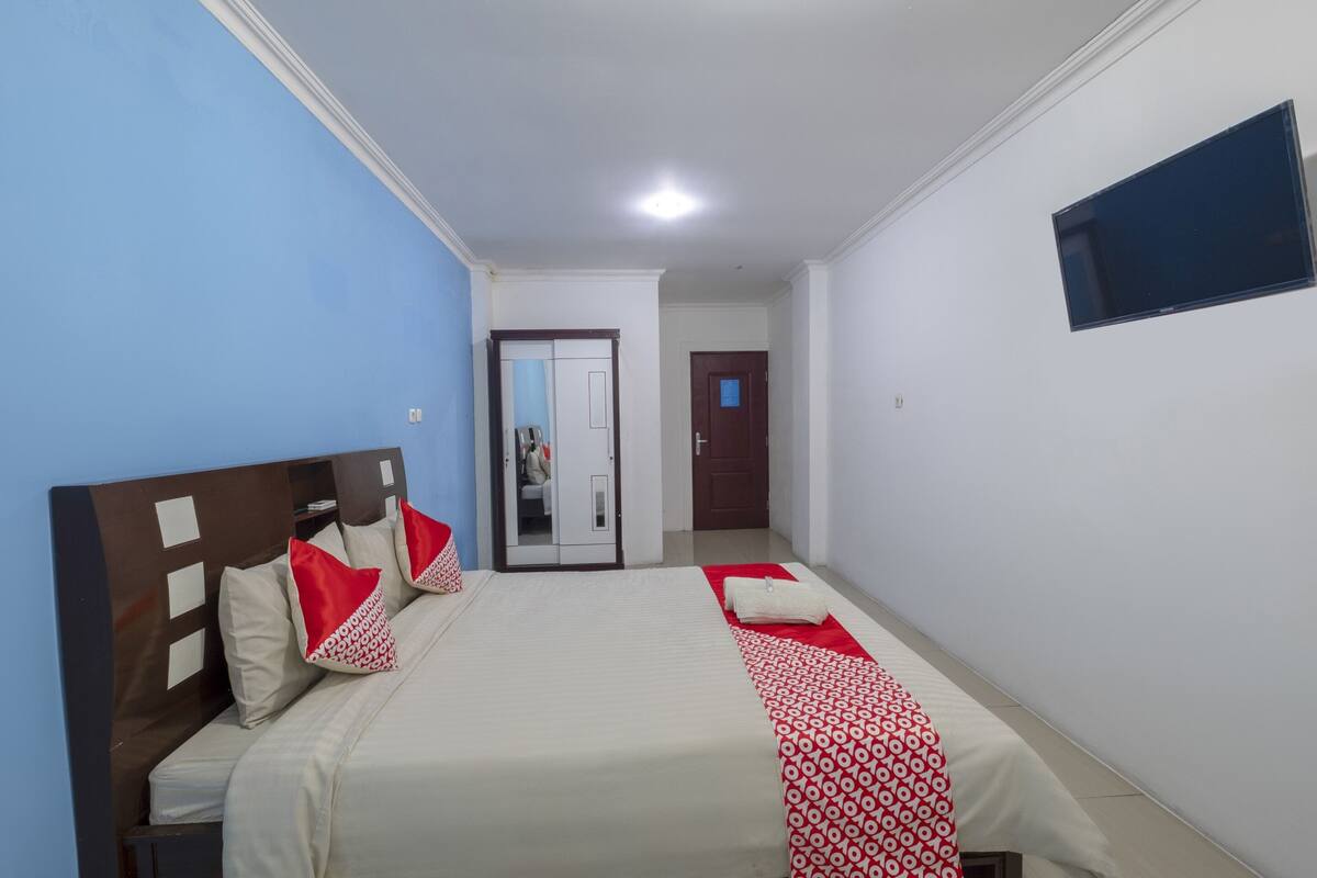Une chambre d’hôtel avec un lit, une armoire, un miroir et une télévision.
