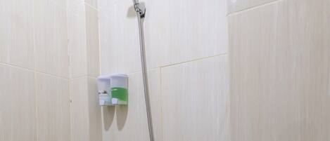 Un baño pequeño con ducha, inodoro y dispensador de jabón en la pared.