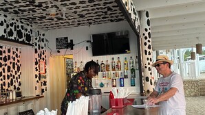 Eine Barbereich mit einer Decke mit Kuhmuster, einer Theke mit einer Speisekarte und verschiedenen Alkoholflaschen.
