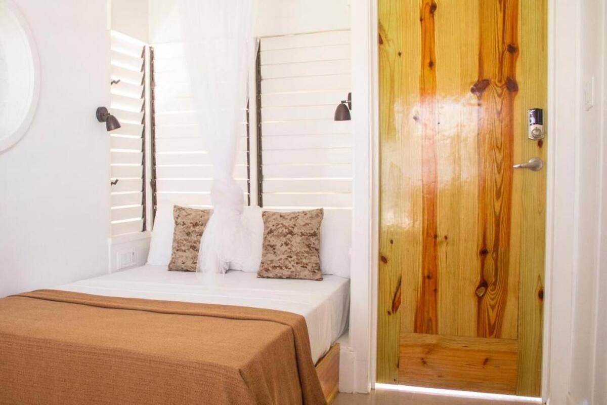 Une chambre à coucher avec un lit, deux oreillers, une fenêtre ronde et une porte en bois.