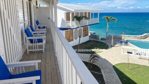 Ein Balkon mit blauen Stühlen, einem Pool und Blick auf den Ozean.
