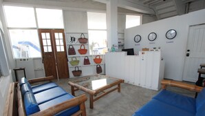 Ein Zimmer mit einer Couch, einem Tisch und einer Wand mit Uhren sowie einem Regal mit Handtaschen.