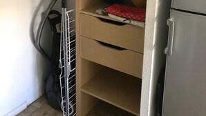 Ein kompaktes Zimmer mit Küchenzeile, einer kleinen Ablage für Kleidung und einem Staubsauger.