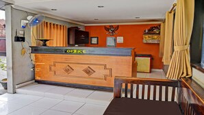 Un espace d’accueil avec un bureau en bois, une enseigne indiquant « BUREAU » et un téléphone fixé au mur.
