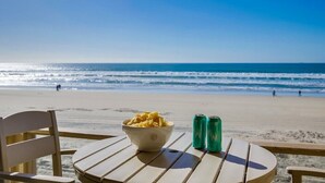 Une table installée sur la plage, avec un bol de chips et deux canettes de soda, d’où l’on a une vue sur l’océan.
