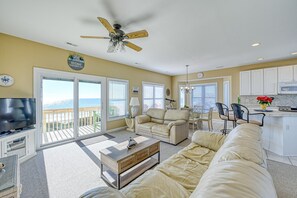 Relax in this comfortable living area with a sofa, coffee table, and TV, plus a balcony offering ocean views.