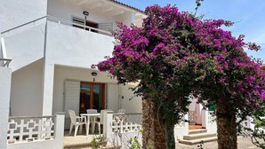 A white building with a balcony, a door, and a table with chairs.