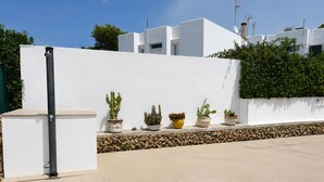 Un bâtiment moderne à l’extérieur blanc, doté d’un socle en pierre et orné de cactus en pot placés sur une corniche.