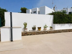 A modern building with a white exterior, a stone base, and potted cacti on a ledge.