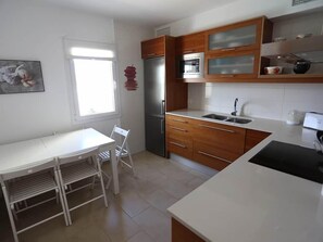 A kitchen with a refrigerator, microwave, sink, and white countertops.