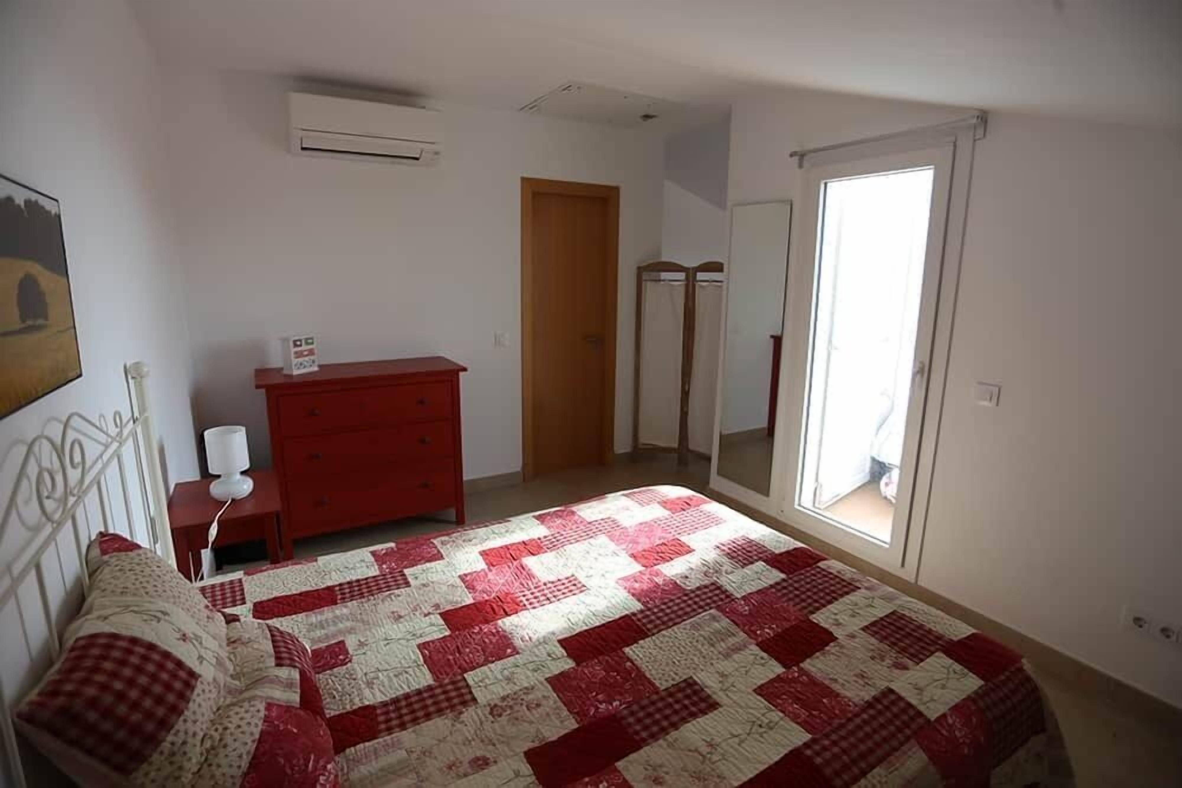 Un dormitorio con cama, cómoda, espejo y puerta que da a otra habitación.