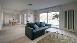 A modern living room with a sofa, a round coffee table, and a dining area with a table and chairs.