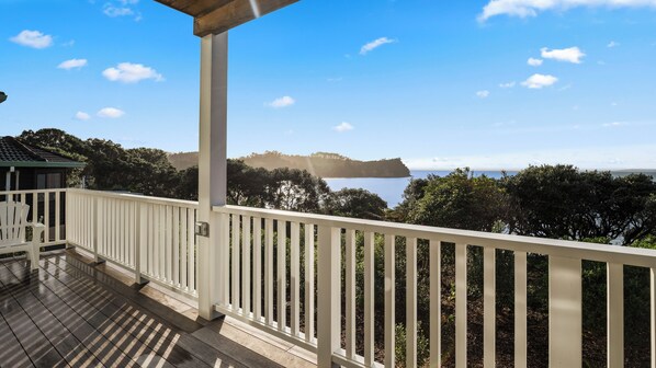 A balcony with a view of a coastal landscape, including a body of water and distant landforms.