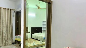A room with a bed, a ceiling fan, and a small table with a chair.