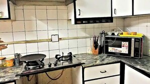 A kitchen with white cabinets, a gas stove, a microwave, and various utensils.