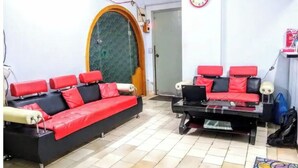 A room with two red and black sofas, a small table, a clock, and a door with a green patterned glass panel.