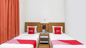 A hotel room with two beds, each with a red and white bedspread and matching pillows. There is a wooden headboard, a small table with a water bottle, and a bulletin board on the wall. - Hotel O Pondok Inap Shofwa 1 (Sidoarjo)