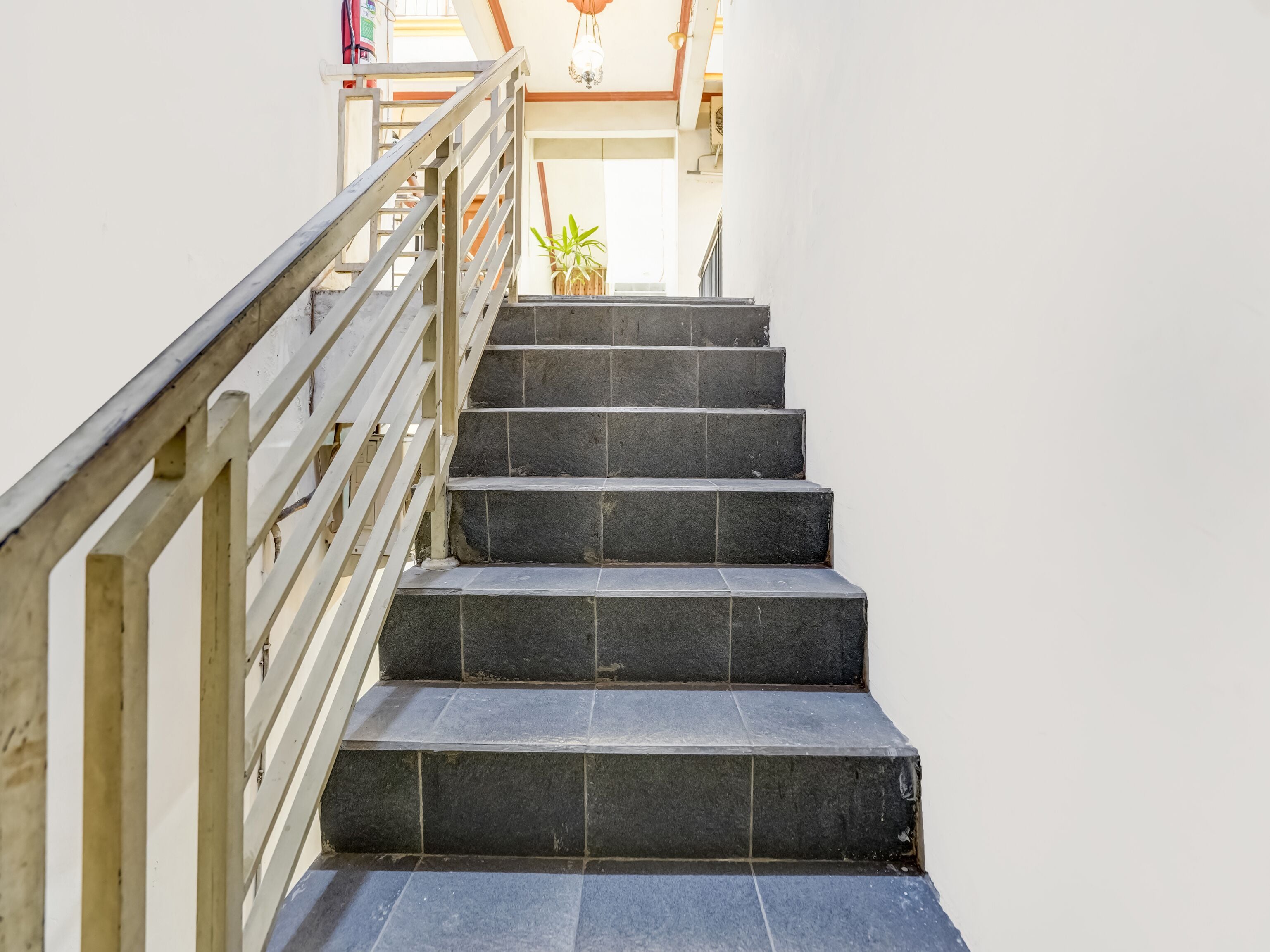 A staircase with dark stone steps and a wooden handrail, leading to an upper floor.