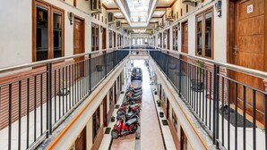 A multi-level corridor with a row of parked scooters, wooden doors, and air conditioning units. - Hotel O Pondok Inap Shofwa 1 (Sidoarjo)