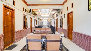 A hotel corridor with wooden doors numbered 21 and 24, a central seating area with two chairs, and a tiled floor. - Hotel O Pondok Inap Shofwa 1 (Sidoarjo)