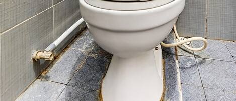 A bathroom with a toilet, tiled walls, and a shower area.