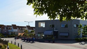 Un edificio moderno con tejado plano, ventanas amplias y una zona de estar al aire libre cubierta.