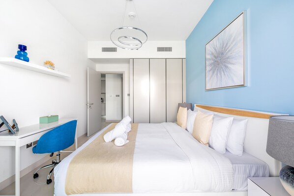 Une chambre d’hôtel moderne équipée d’un lit, d’un bureau, d’une chaise et d’une table de chevet.