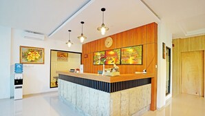 A reception area with a wooden counter, stone base, and hanging pendant lights. - Collection O 90876 Pecatu Residences (Pecatu)