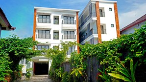 A multi-story residential building with balconies, a garage entrance, and lush greenery surrounding the property. - Collection O 90876 Pecatu Residences (Pecatu)