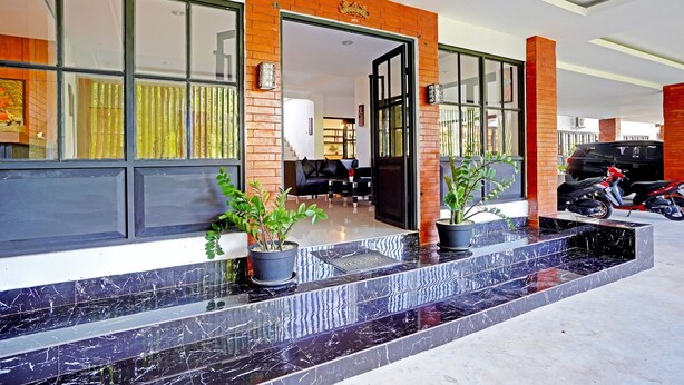 A hotel entrance with a modern design, featuring a brick facade, large windows, and a marble reception area. - Collection O 90876 Pecatu Residences (Pecatu)