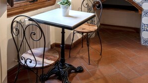 A rustic kitchen with a wooden table and chairs, a tiled backsplash, and a fireplace.