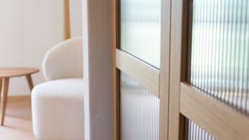Una habitación con ventana de madera, un sofá blanco y una pequeña mesa de madera.
