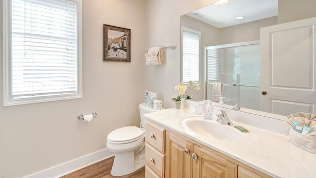 A modern bathroom with a large mirror, white toilet, and vanity with a sink and cabinet. - Wintergreens R910- Mtn Condo/View, Gated Resort, Indoor/Outdoor Pools & Hot Tub (Banner Elk)