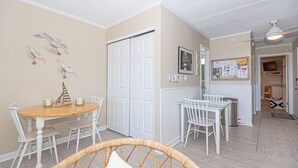 A dining area with a round table and chairs, a white door, and a bulletin board with papers.