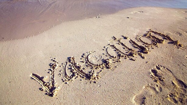 Ein Strand mit Fußabdrücken und dem Wort 'welcome' im Sand geschrieben.