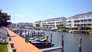 Ein Hafen mit vertäuten Booten, einer Holzpromenade und mehrstöckigen Gebäuden mit Balkonen.
