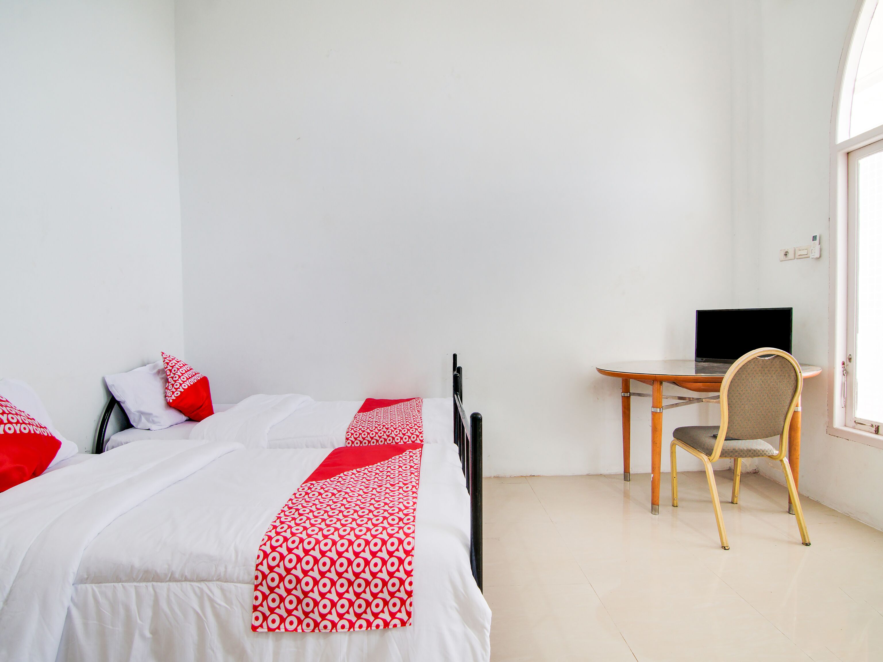 A bedroom with two beds, a desk with a computer, and a chair.