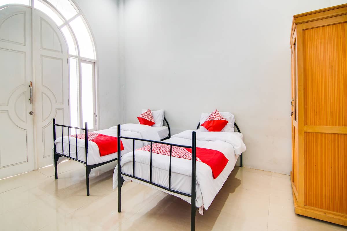 Ein Zimmer mit zwei Betten, einem Kleiderschrank und einem großen Bogenfenster.