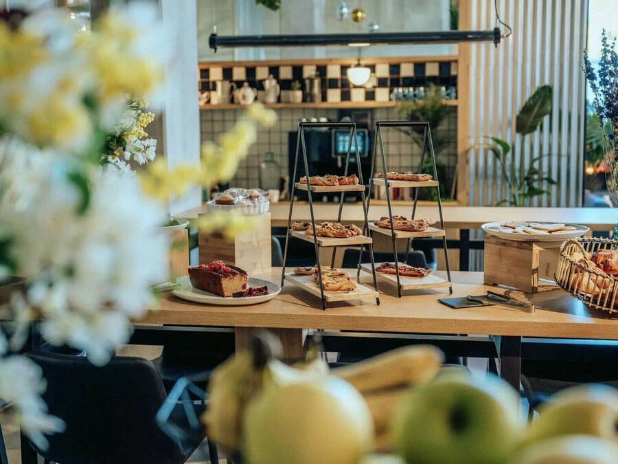 A café with a wooden table displaying pastries and a tiered stand with baked goods.