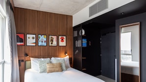 Una habitación de hotel moderna con una cama grande, paneles de madera y obras de arte enmarcadas en la pared.