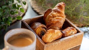 A wooden box containing croissants and a cup of coffee on a table.