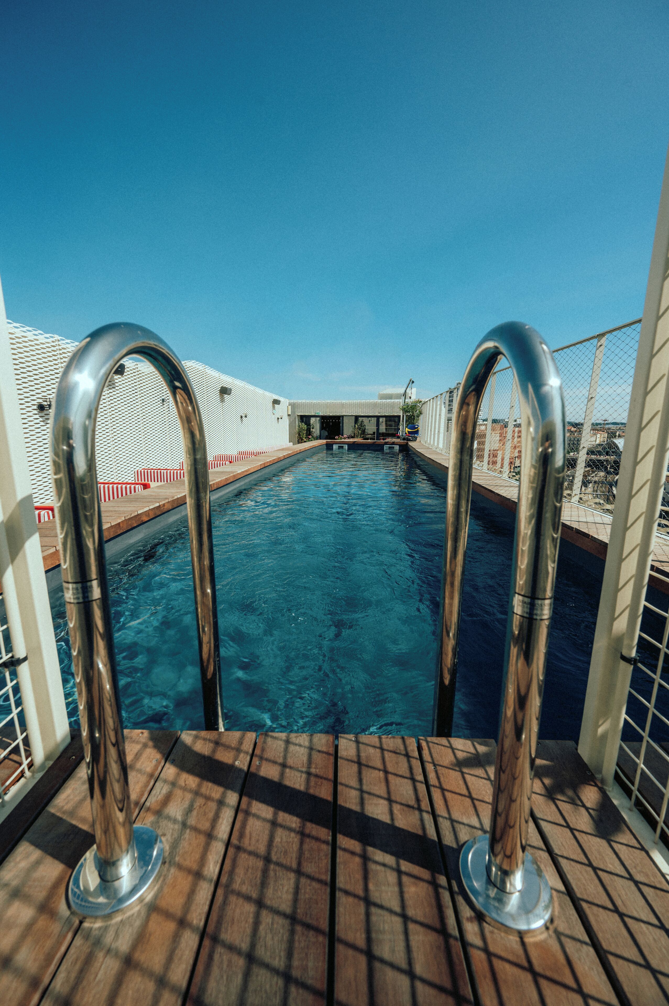 Un espace piscine doté de rampes en métal et d’une terrasse en bois.