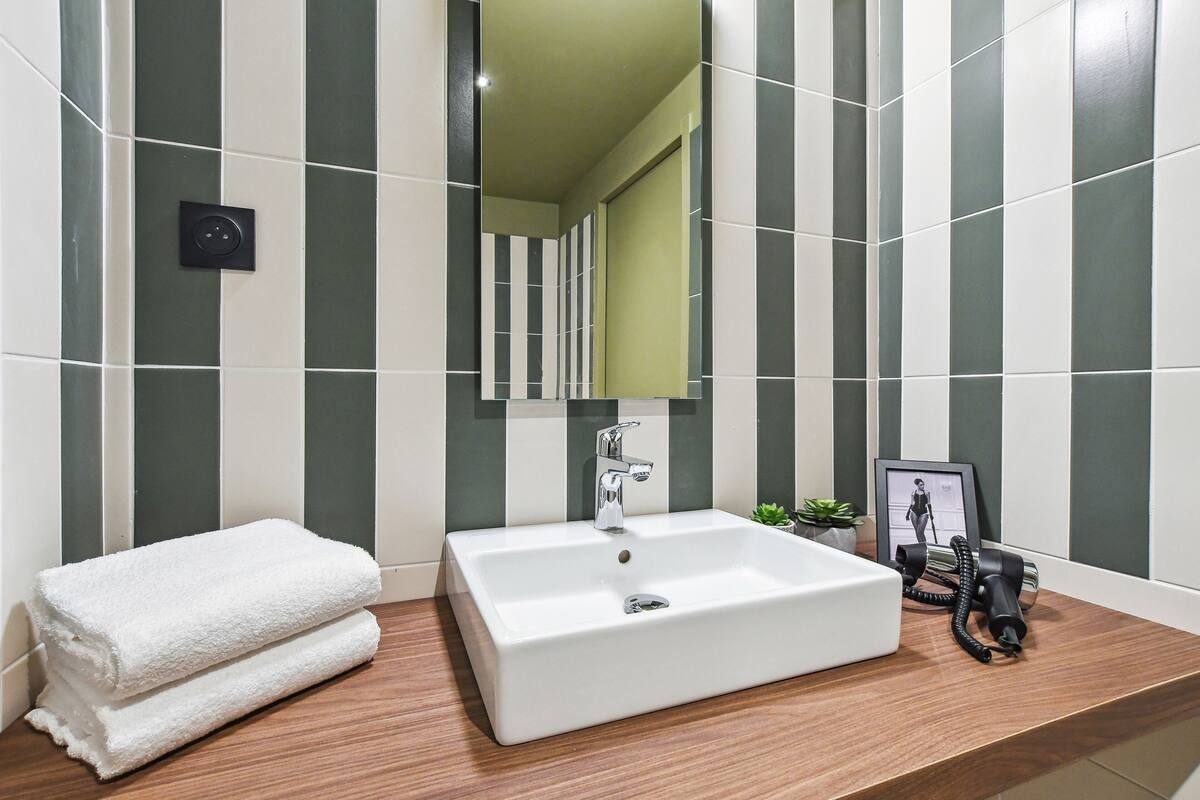 A bathroom with a white sink, a mirror, a towel, and a small plant.