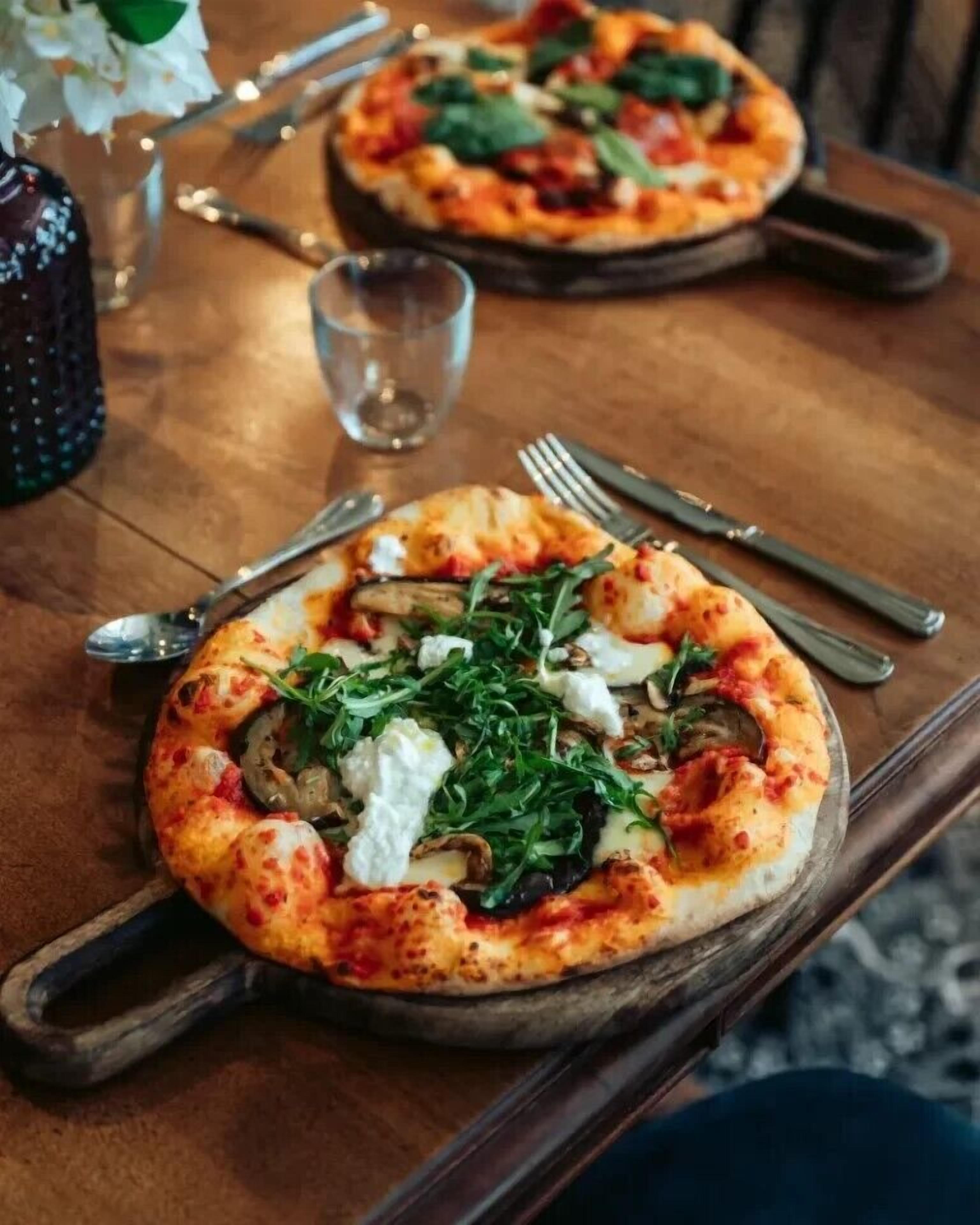 Une pizza garnie, servie sur une planche en bois.